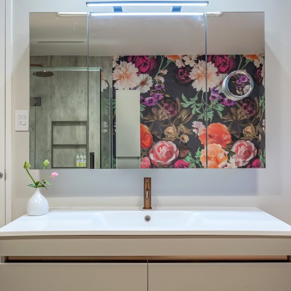 Vanity and mirror reflecting bold wallpaper